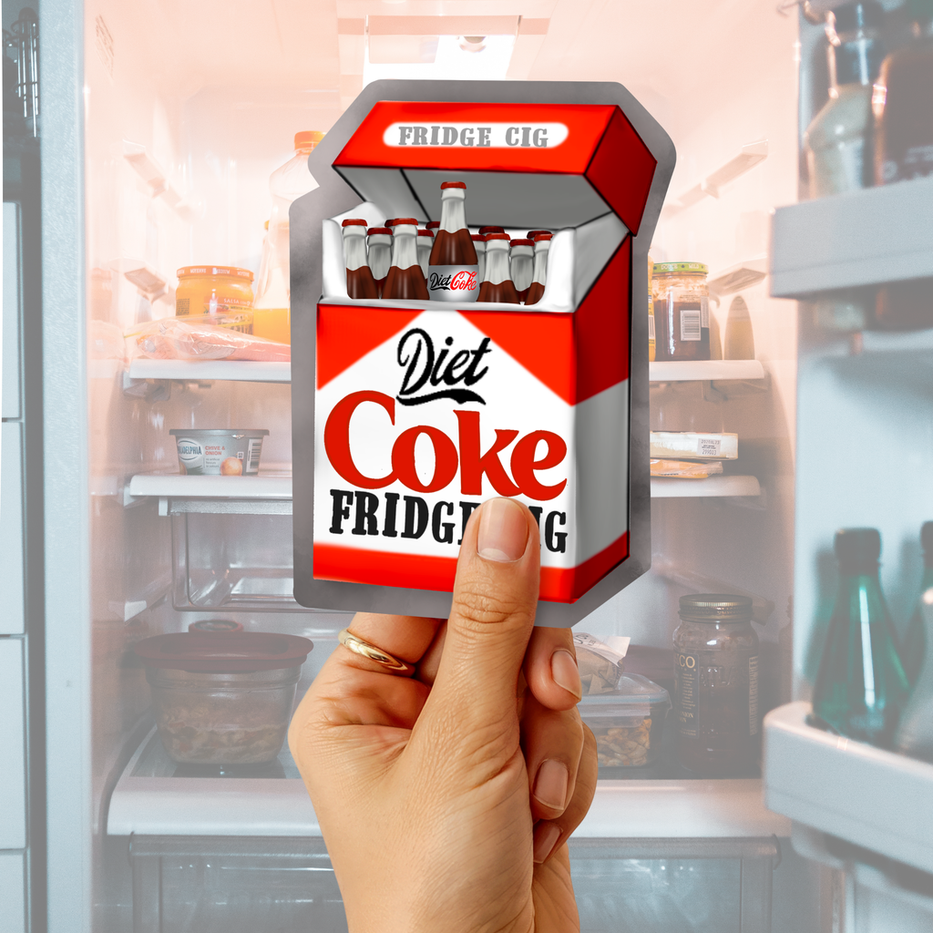Hand holding a Diet Coke “Fridge Cig” sticker in front of an open refrigerator background.