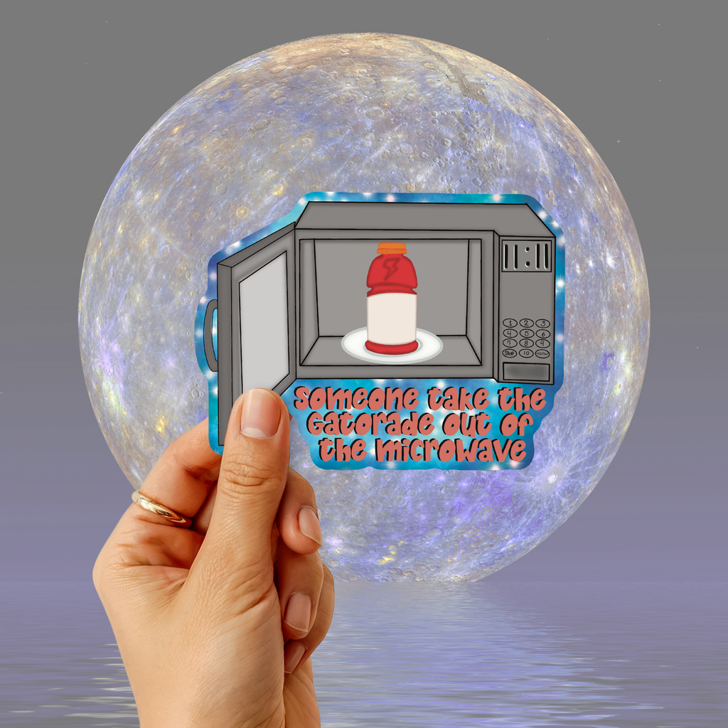 A hand holds a die-cut sticker in front of a large moon graphic. The sticker shows an open microwave with a red-and-white mug inside and the text 'someone take the caterade out of the microwave' in pink outlined letters.