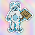 Close-up vinyl sticker of a fluffy blue and white yeti holding a motivational wooden sign that says “If you can believe in me you can believe in yourself.”