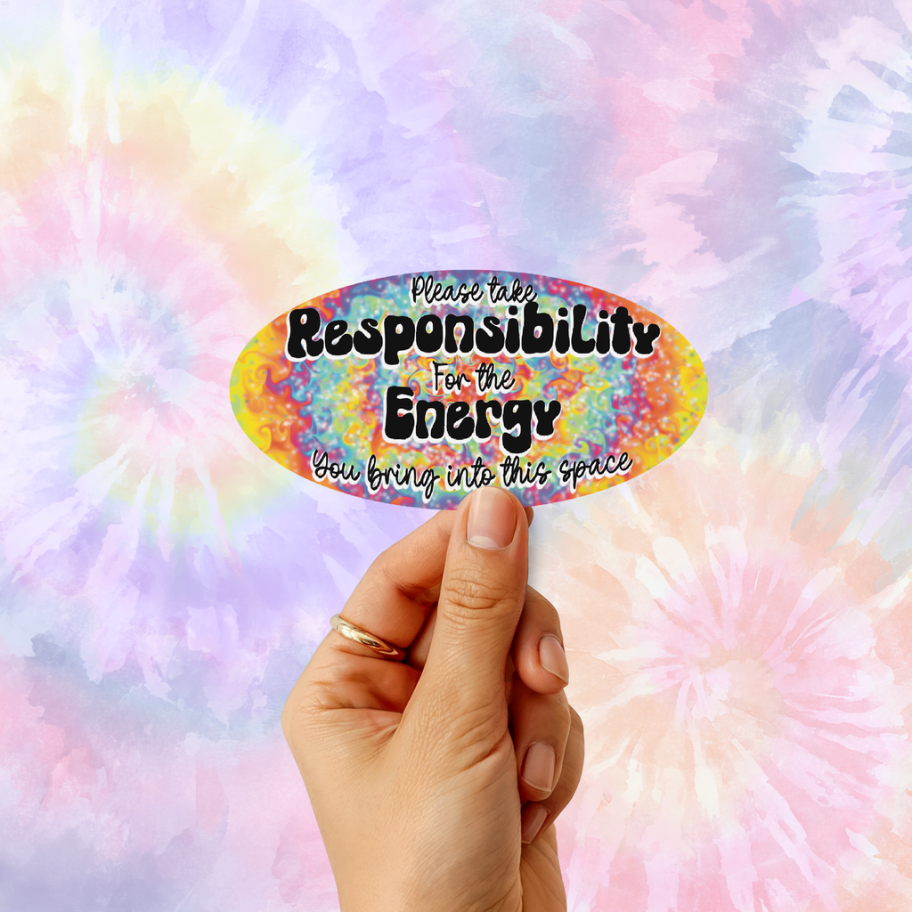 A hand holds a colorful oval sticker with the text 'Please take Responsibility For the Energy You bring into this space' against a pastel tie-dye background.