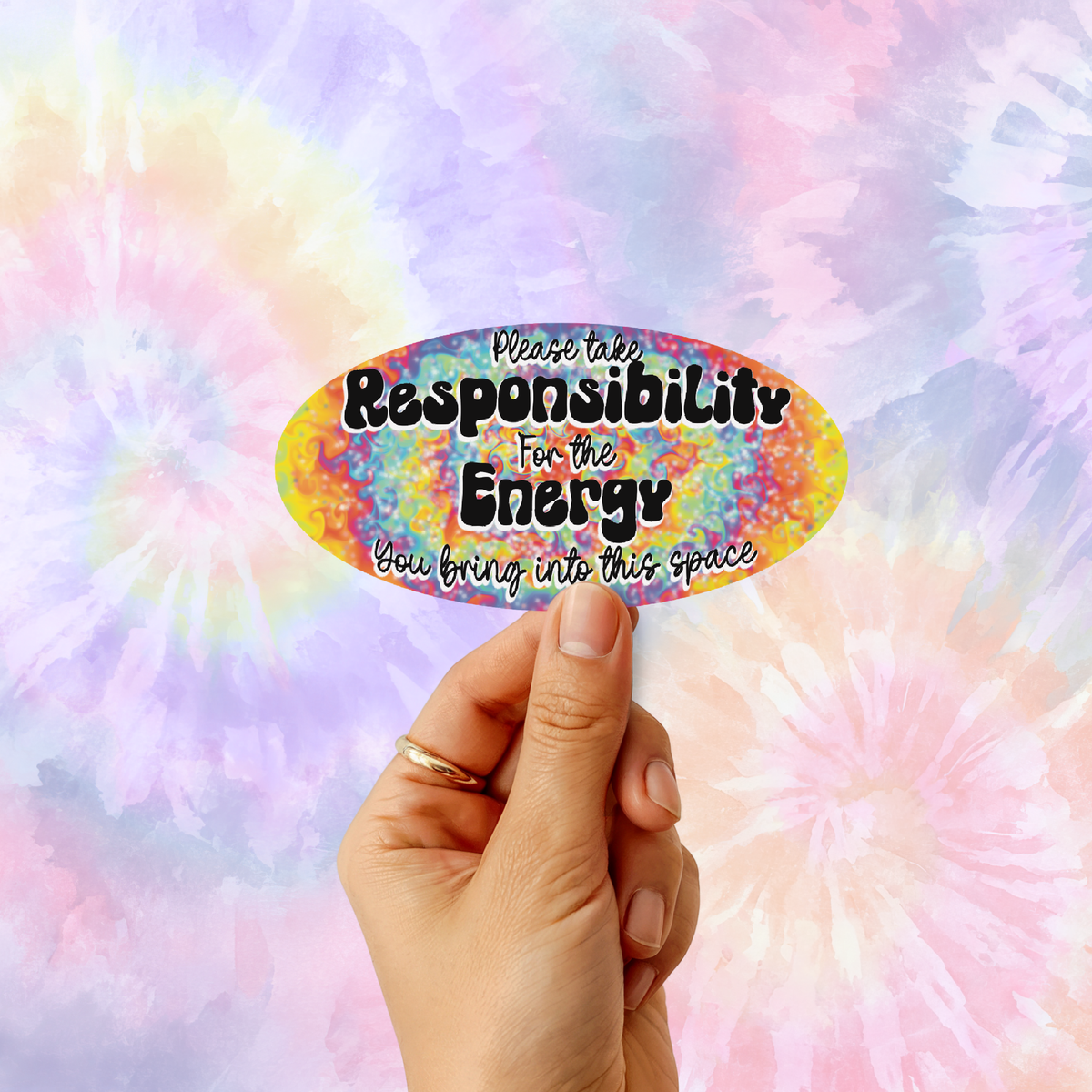 A hand holds a colorful oval sticker with the text 'Please take Responsibility For the Energy You bring into this space' against a pastel tie-dye background.