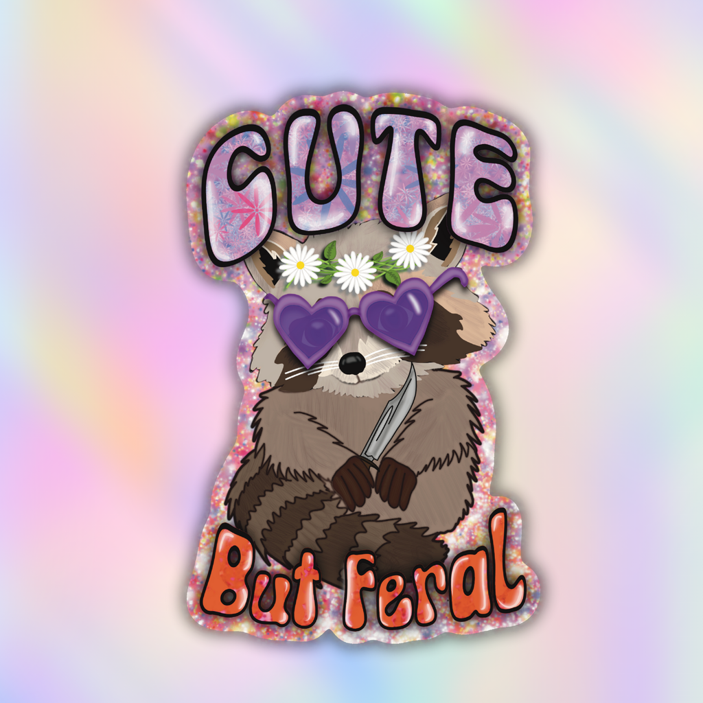 A die-cut sticker featuring a cartoon raccoon with white daisies on its head, purple heart-shaped sunglasses, and a knife, with the text 'CUTE But Feral' in stylized lettering, shown on a pastel iridescent background.