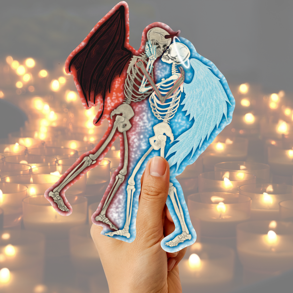 A hand holds two die-cut sticker-like figures shaped like winged skeletons embracing. One figure is red/pink with dark wings, and the other is blue with light wings.