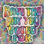 A die-cut sticker with the text 'HAVE THE DAY YOU VOTED FOR' in colorful rainbow tie-dye bubble letters with black outlines, set against a matching patterned background.