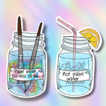 Two die-cut vinyl stickers featuring illustrated mason jars with straws and paintbrushes, shown on a pastel rainbow gradient background. The left sticker says 'Paint water.
