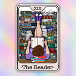 A tarot card style illustration labeled 'XIII The Reader' showing a person lying on their back in a book-filled library, holding an open book with their legs raised. The card is centered on a pastel iridescent gradient background.