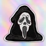 A die-cut sticker featuring a Ghostface-style hooded mask design with intricate black and white line art patterns, shown against a pastel rainbow gradient background.