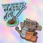 Two garden-themed stickers with gardening tools and text on a colorful background