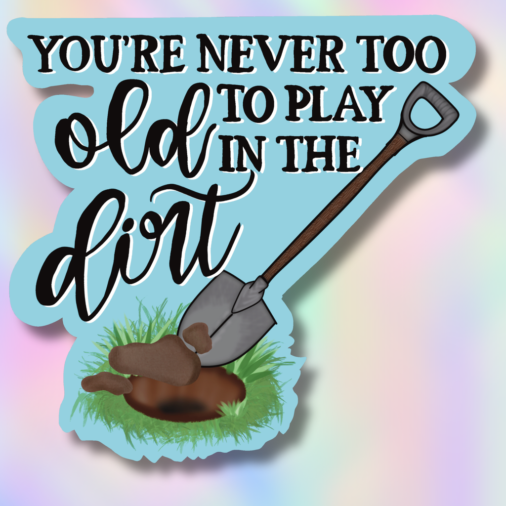 Decorative sign with a shovel and text 'You're never too old to play in the dirt' on a colorful background.