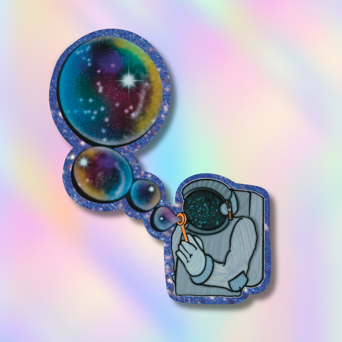 A die-cut sticker featuring a whimsical illustration of an astronaut blowing a bubble that pops into a galaxy, shown on a pastel iridescent background.