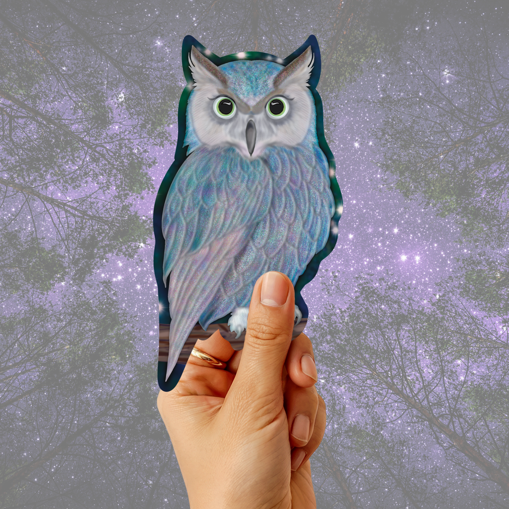 A hand holds a die-cut sticker of a detailed owl with iridescent blue, purple, and gray feathers against a blurred purple starry night sky background.