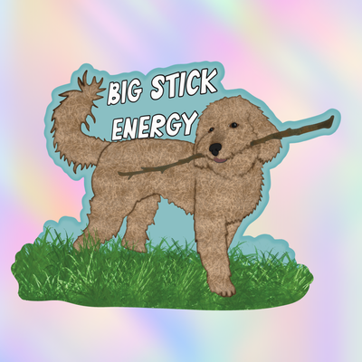 Close-up vinyl sticker of a fluffy doodle-style dog holding a large stick with the phrase “Big Stick Energy.”