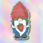 A strawberry gnome sticker or decal featuring a cute gnome holding a strawberry, with a light blue border and a soft pastel rainbow gradient background.