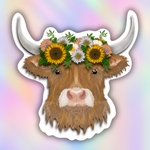A die-cut sticker featuring a stylized brown highland cow head with long white horns, wearing a floral crown of sunflowers, daisies, and small pink flowers with green leaves, shown on a pastel rainbow gradient background.